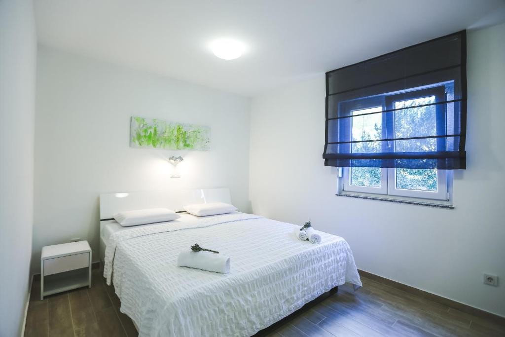 a white bedroom with a bed and a window at Apartments Sesar in Rab