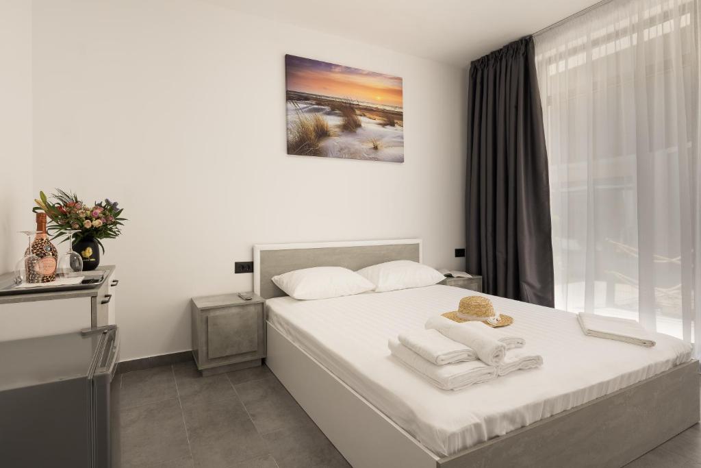 a bedroom with a white bed with towels on it at Flamingo Corbu Resort in Corbu