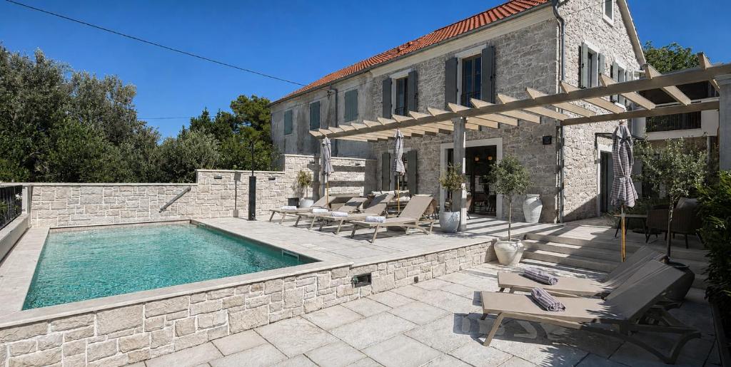 a house with a swimming pool next to a building at Heritage Villa Francheza-Elegant Stone villa near the Beach, Pašman Island , Ugrinić in Ugrinići