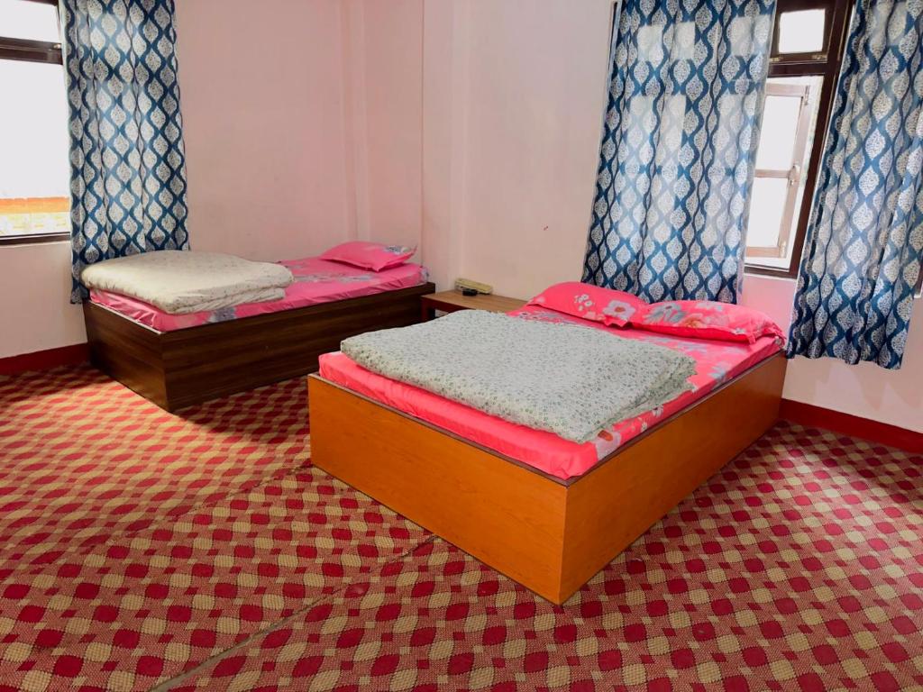 two twin beds in a room with red and blue curtains at new hotel gaule in Bālāju