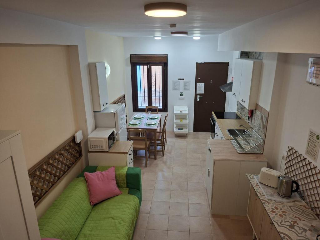 a living room with a green couch and a kitchen at Alcazaba Home in Almería