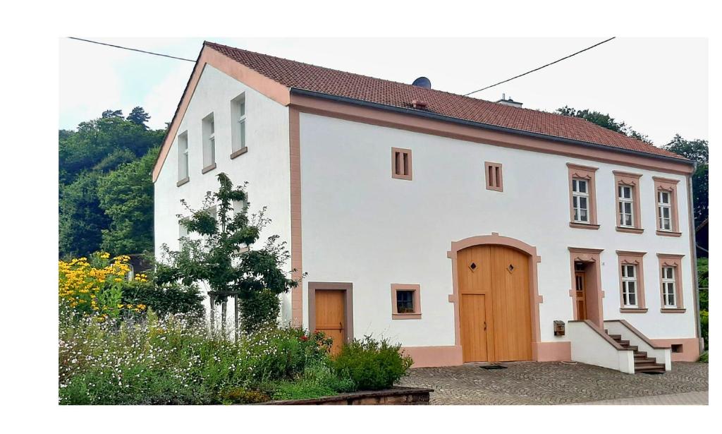 a white house with a wooden door and a yard at Ferienwohnungen Zur Tenne in Beckingen