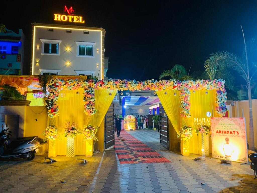 a hotel entrance with a yellow gate and flowers at MAHAMAYA CONVENTION and HOTEL in Mālatīpātpur