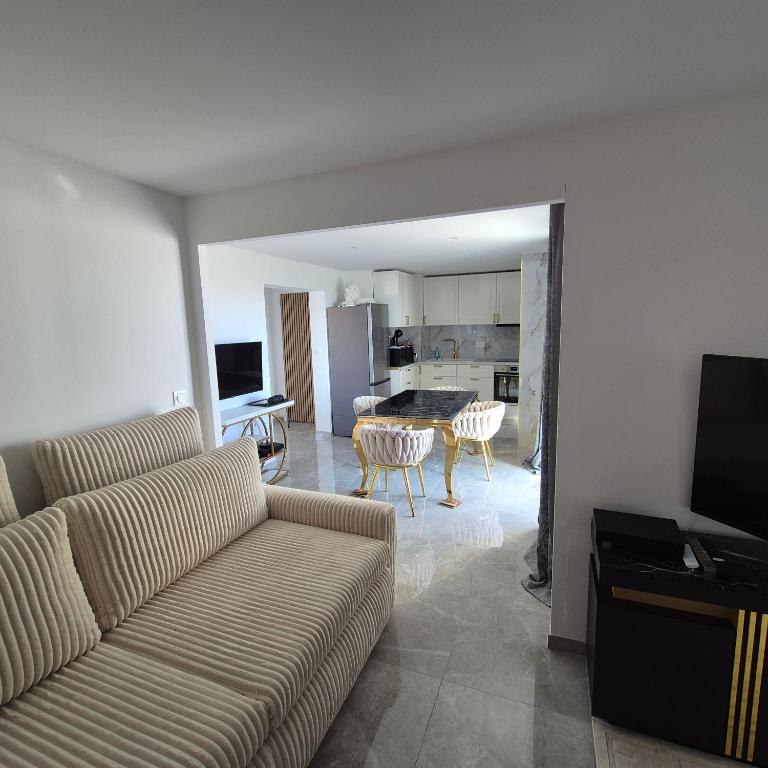 a living room with a couch and a kitchen at Appartement neuf full équipe in Palavas-les-Flots