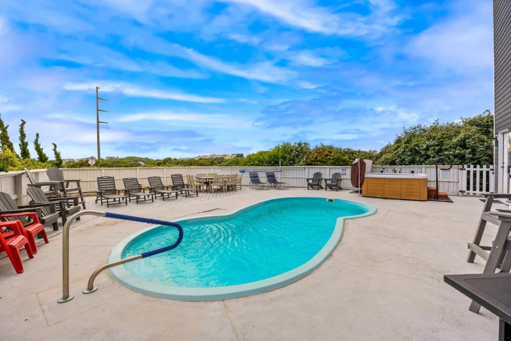 a swimming pool with chairs and tables on a patio at 6170 - Poolside Paradise in Nags Head