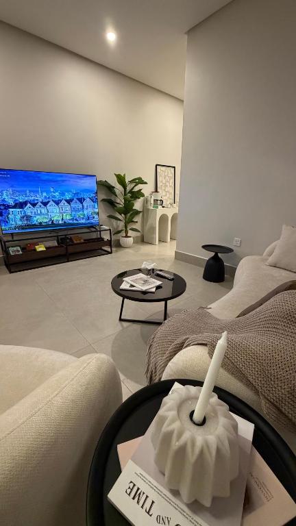 a living room with two beds and a flat screen tv at AURA Stay in Dammam