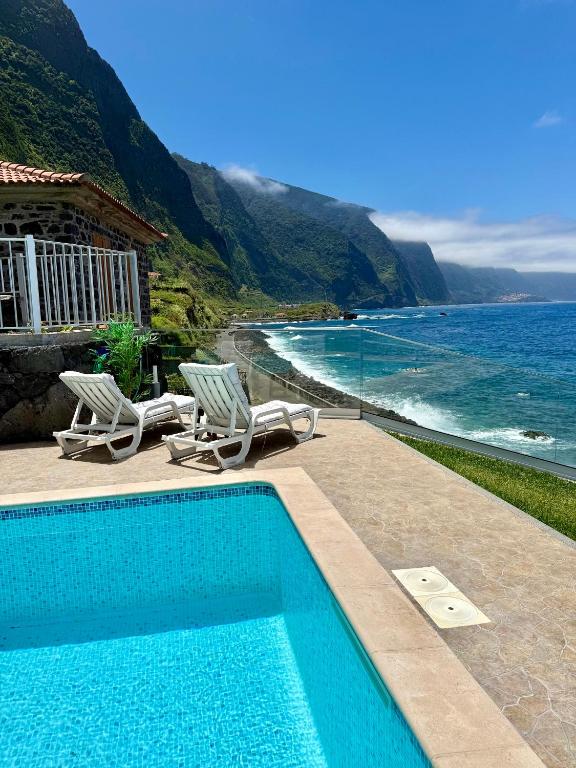 a swimming pool with two chairs and the ocean at Casa do mar in São Vicente