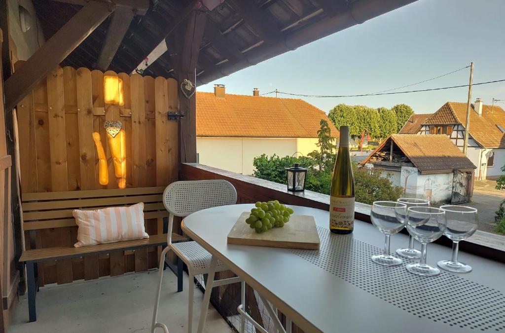 a table with wine glasses and a bottle on a balcony at AlsAppart, duplex climatisé à 5 min de Colmar in Sainte-Croix-en-Plaine