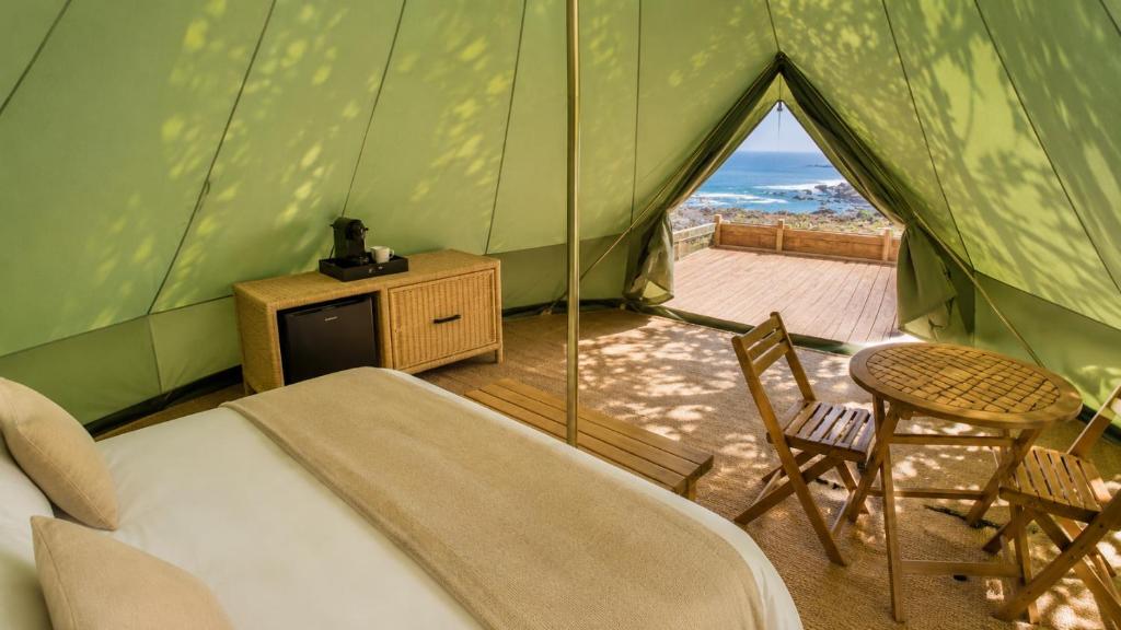 a room with a bed and chairs in a tent at La Ballenera Lodge in Guaquen