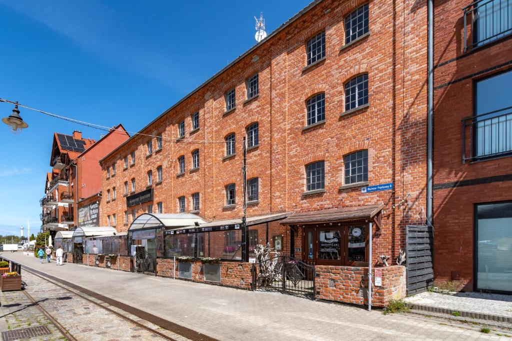 ein großes rotes Backsteingebäude an einer Straße in der Unterkunft Hotel Bulwar Ustka in Ustka