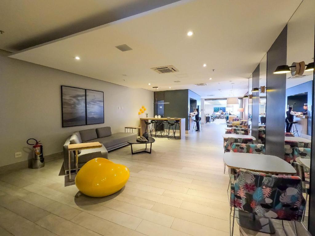 a lobby with a yellow ottoman and tables and chairs at Stay Inn Santos in Santos
