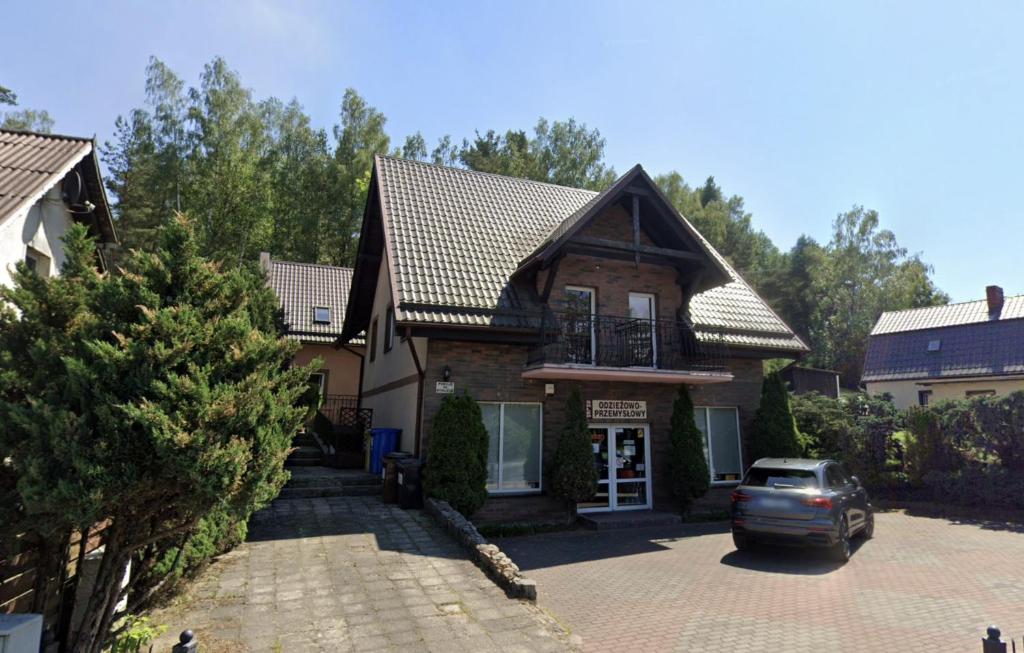 a house with a car parked in a driveway at Pokoje Gościnne AKACJA in Swornegacie