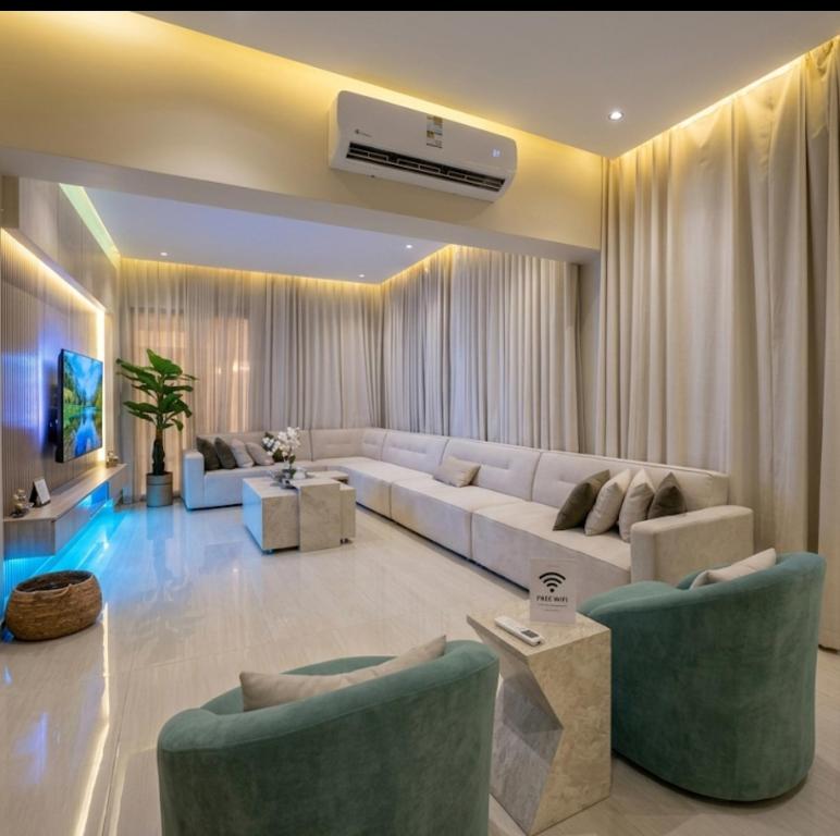 a living room with a white couch and chairs at Luna Villa in Al Khobar