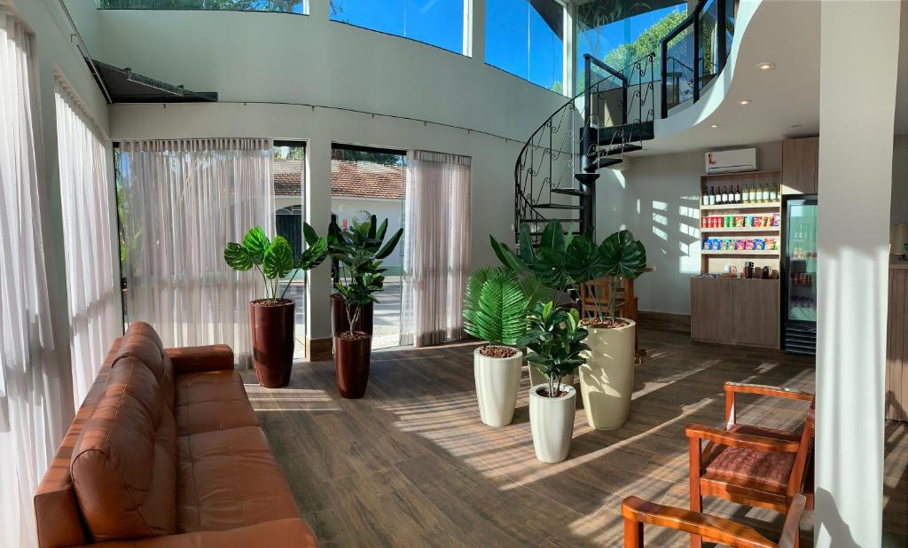 a living room with a couch and potted plants at Ipê Hotel Jardins in Ponta Grossa