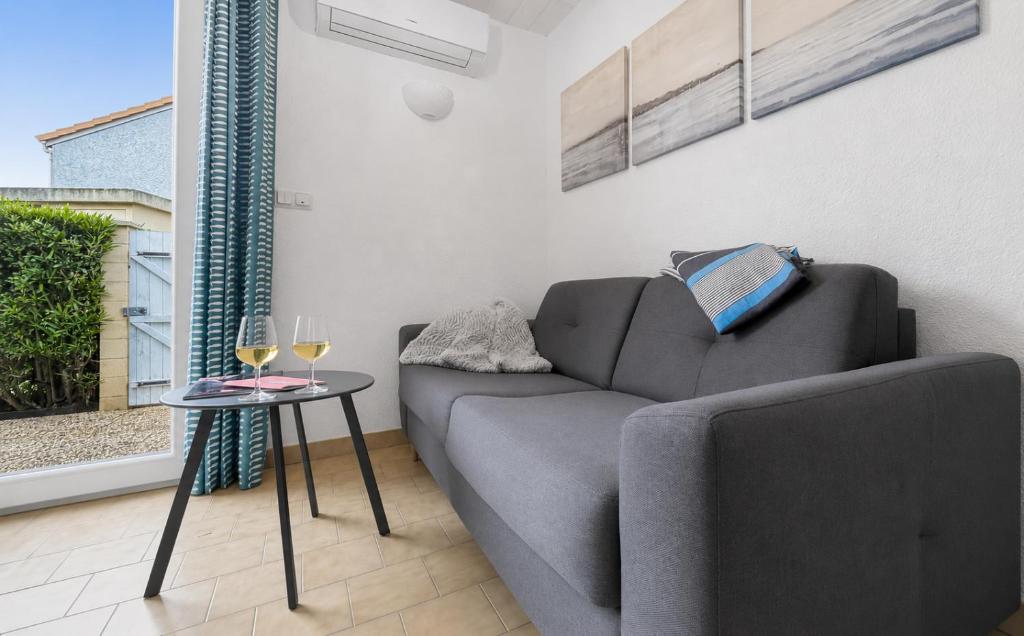 a living room with a couch and a table with wine glasses at Petit cocon, parking et piscine à Marseillan in Marseillan