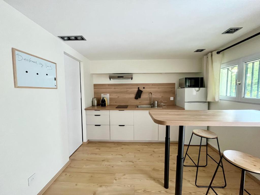 a kitchen with white cabinets and a wooden table at Le Studio nature de La Pra in Herbeys
