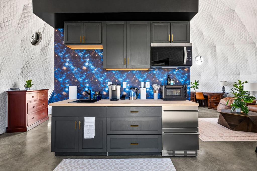 a kitchen with gray cabinets and a blue wall at Stargazer Dome Retreat in San Marcos