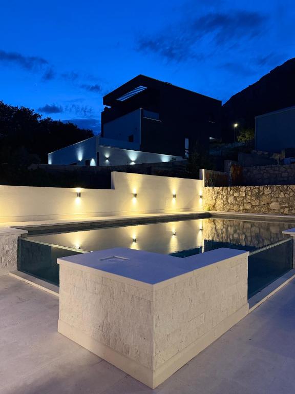 a swimming pool with lights in front of a building at Apartments M&E in Mokošica