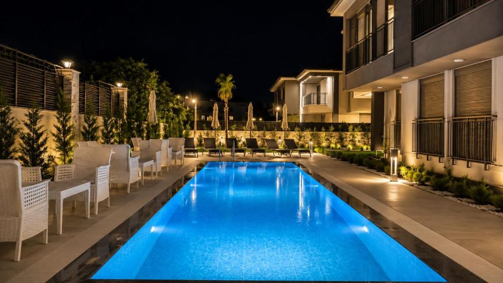 a swimming pool with chairs and a building at night at Busera Vida Inn in Ilıcaköy