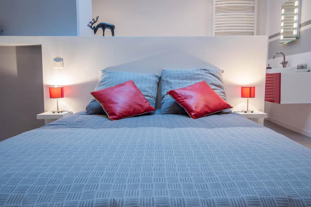 um quarto com uma cama com duas almofadas vermelhas em Chambres d'hôtes L'Ecrit Vin em Rustiques