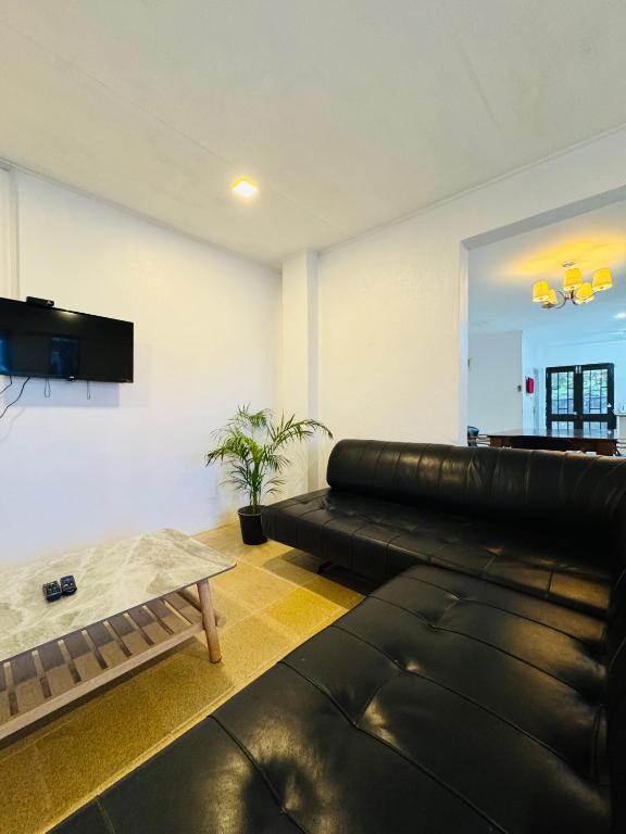 a living room with a black leather couch and a table at Three bedroom apartment in Suva