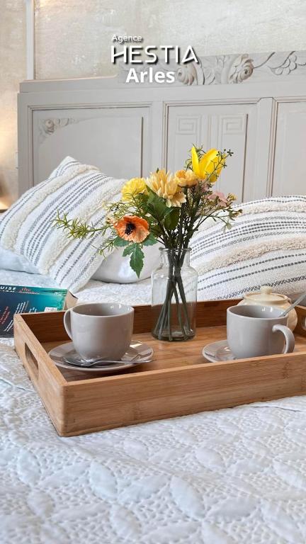 a wooden tray with cups and flowers on a bed at La Maison des Hautures - Ancien Couvent avec Extérieur Proche Arénes- Idéal Familles ou groupe in Arles