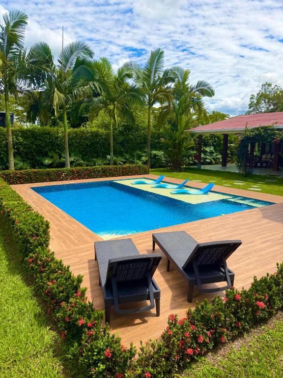 a swimming pool with two chairs and a table at Casa Carmentea Villa Privada in Acacías