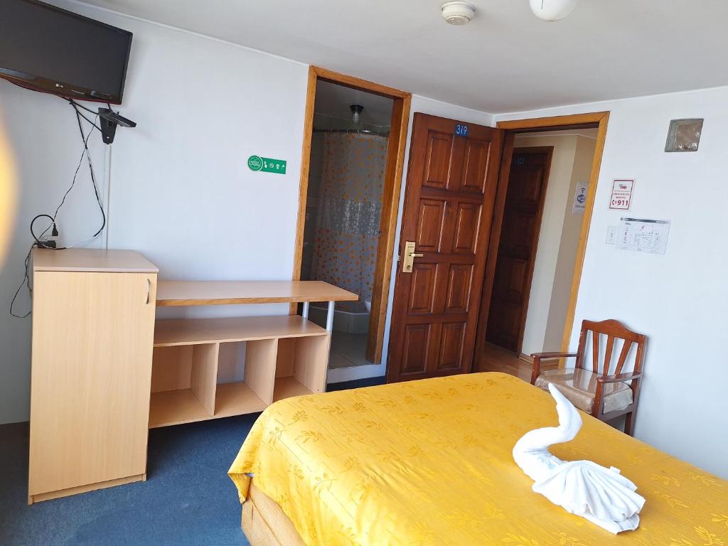 a room with a bed and a desk and a television at Hotel Calima in Quito