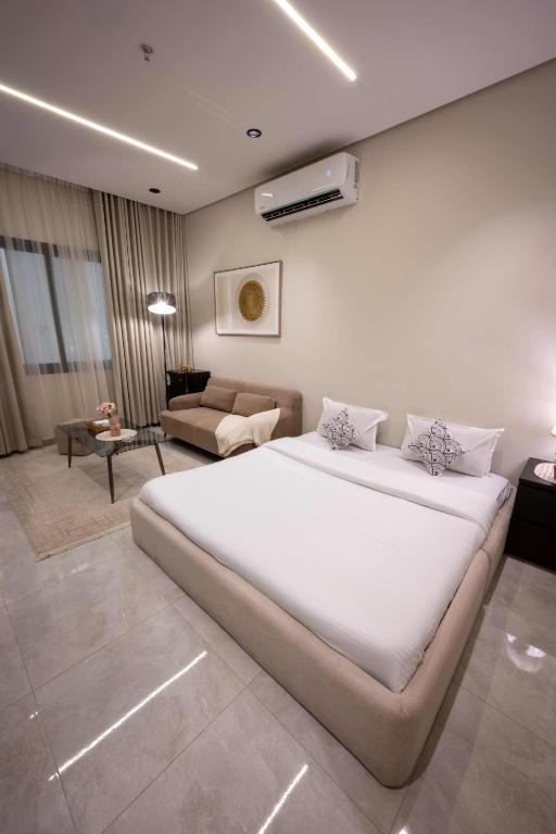 a bedroom with a large white bed and a living room at استديو خاص in Al Khobar
