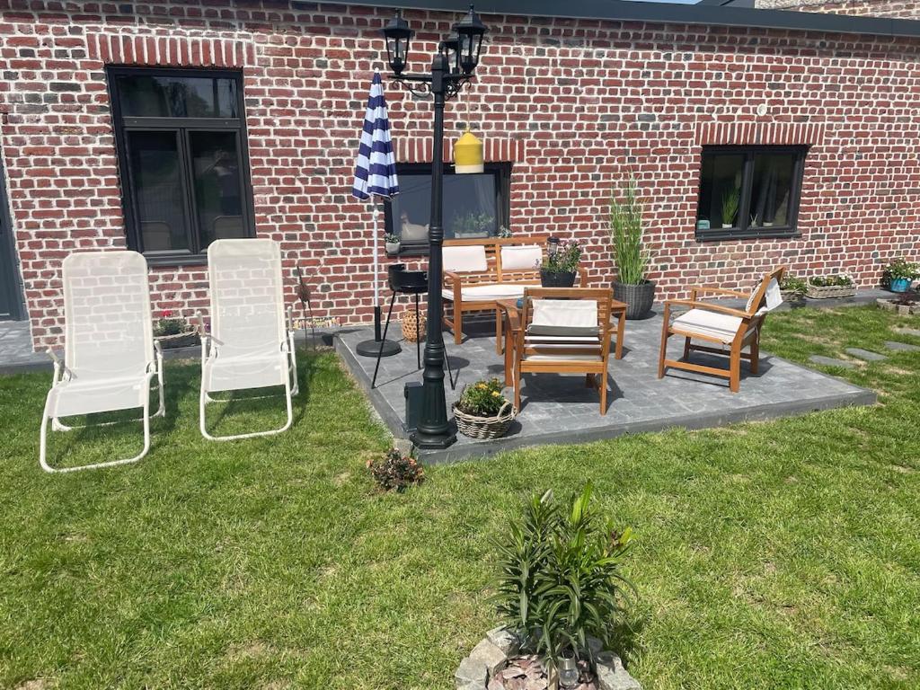 a group of chairs and a table with an umbrella at Le gîte des Romains in Anor