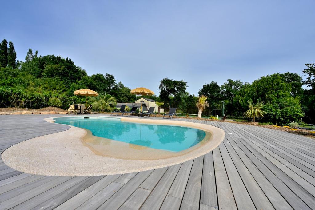 a swimming pool on a deck with a wooden floor at Le Nid de Mazerolles in Sucé