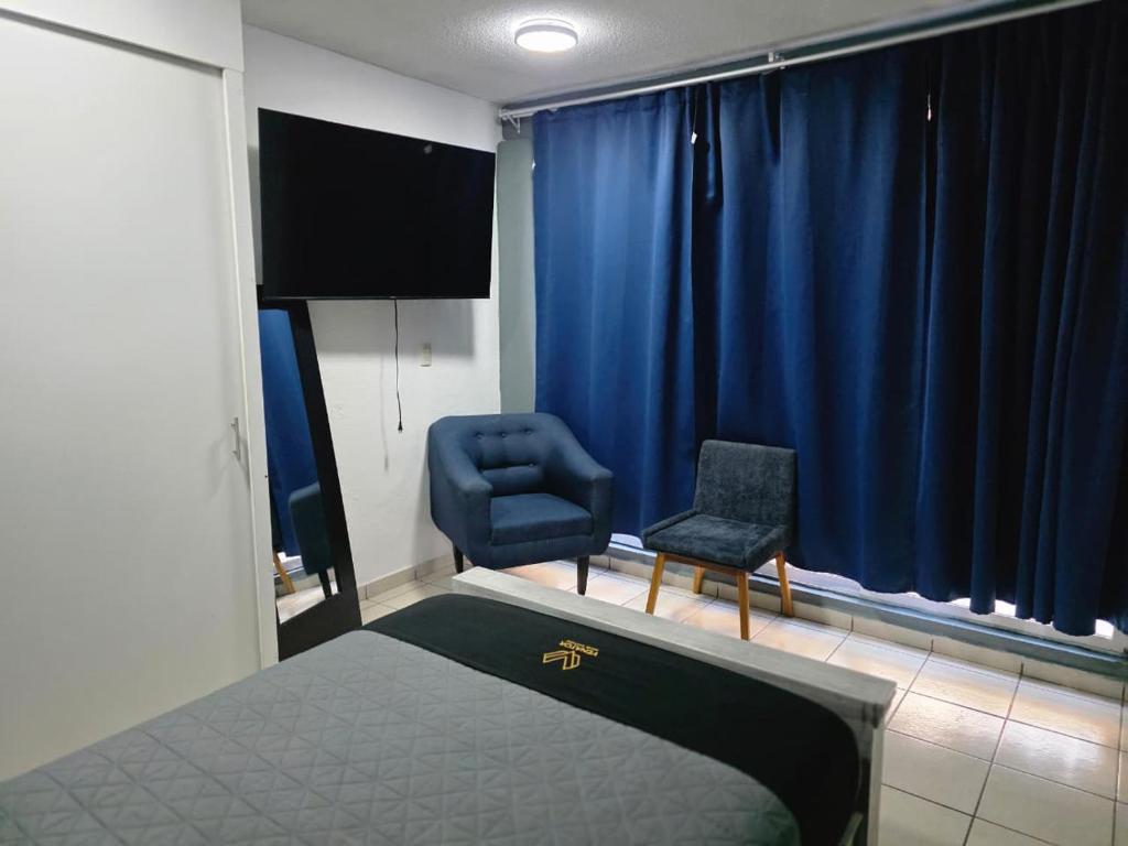 a bedroom with a bed and a chair and blue curtains at 10 VENATOR House Boutique in León