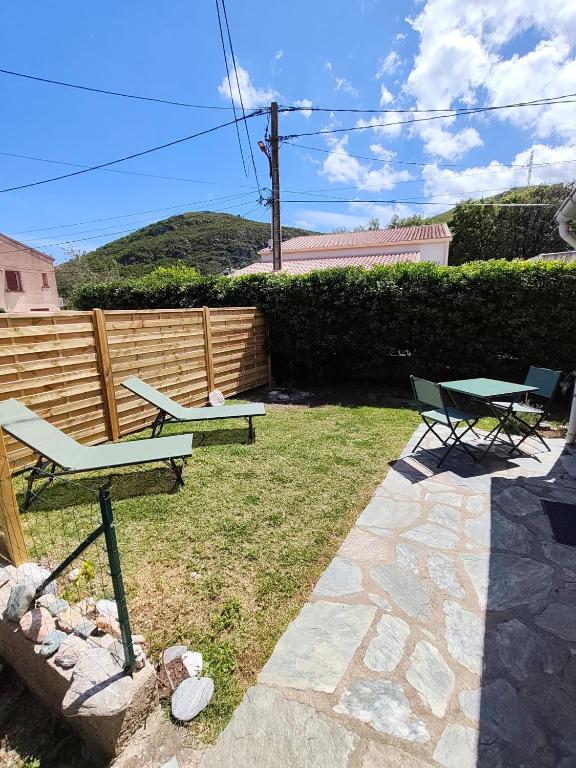 a backyard with two chairs and a table and a bench at la crique in Sisco