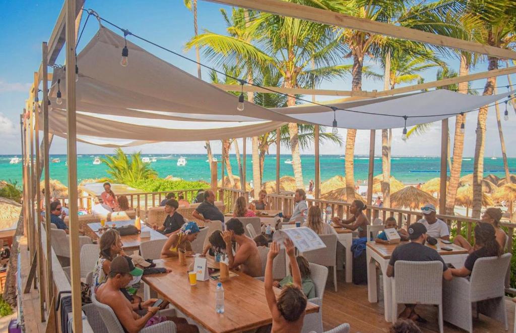 a group of people sitting at tables on the beach at DUKASI ESCAPE playa LOS CORALES in Punta Cana