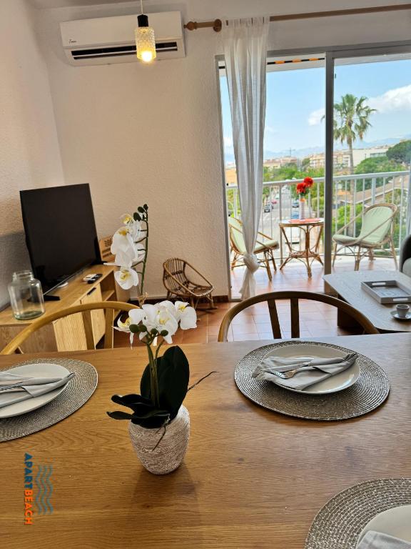 a dining room table with plates and flowers on it at APARTBEACH BALANDRO VISTAS MAR in Cambrils