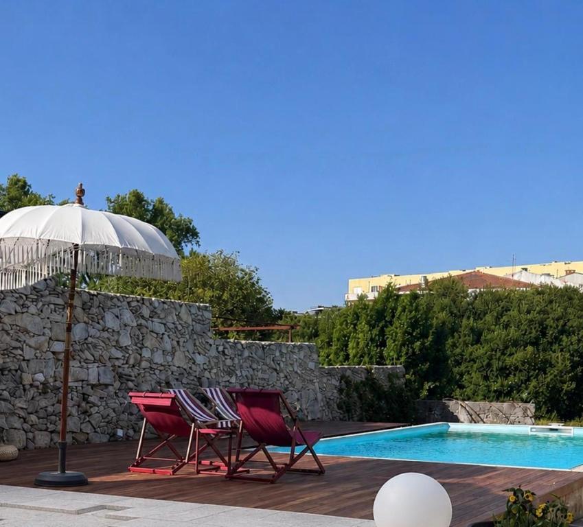 two chairs and an umbrella next to a swimming pool at Casa de Ramalde in Porto