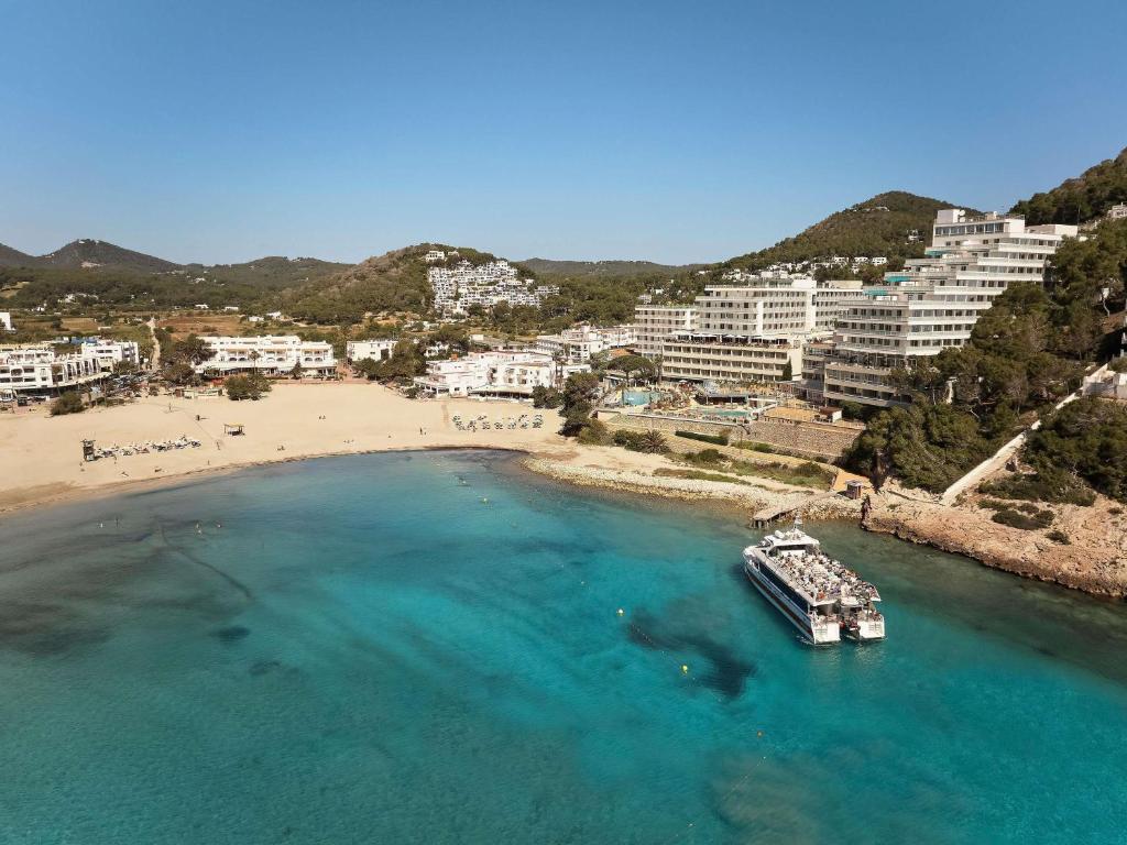 an aerial view of a beach with a boat in the water at Hyde Ibiza Beach Resort by Accor in Cala Llonga
