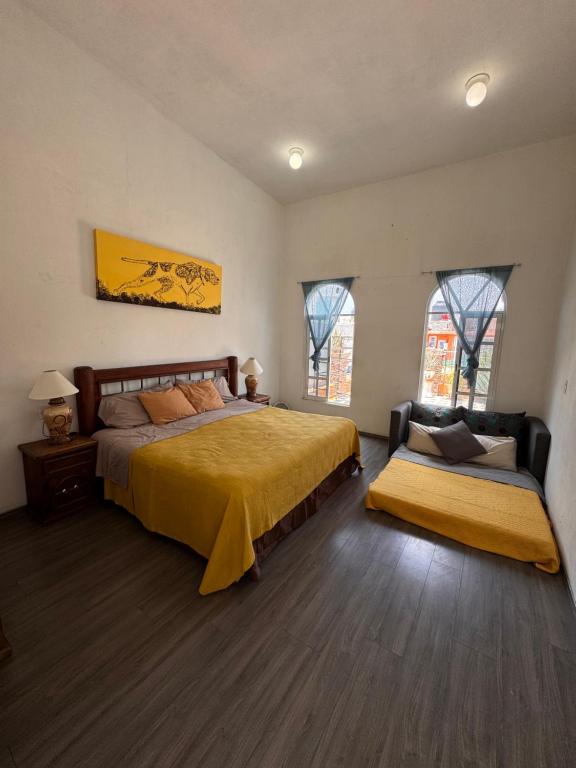 a bedroom with a bed and a couch and two windows at Mexican House in Mexico City