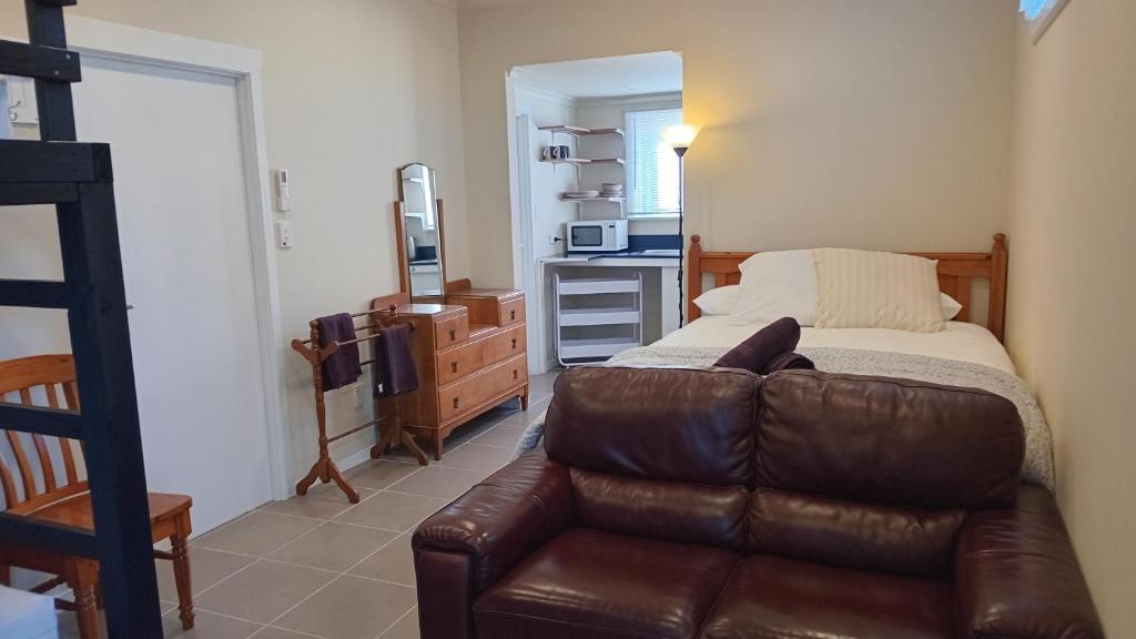 a living room with a leather couch and a bedroom at The Central Apartment in Geraldine