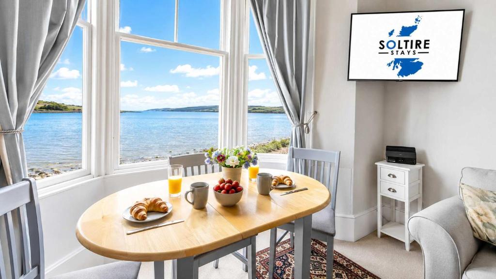 a dining room with a table and a view of the ocean at Govandale Seaviews in Kingarth