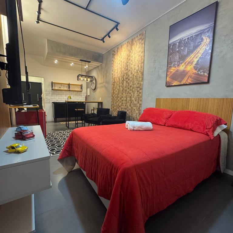 a bedroom with a red bed and a living room at Studio Industrial in Niterói