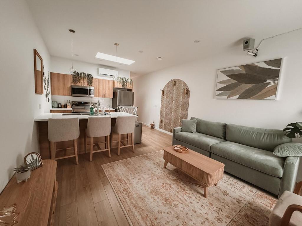 a living room with a green couch and a kitchen at Private Boho Tiny Home - Lakes, Wineries, Hike, Ski in Kelowna