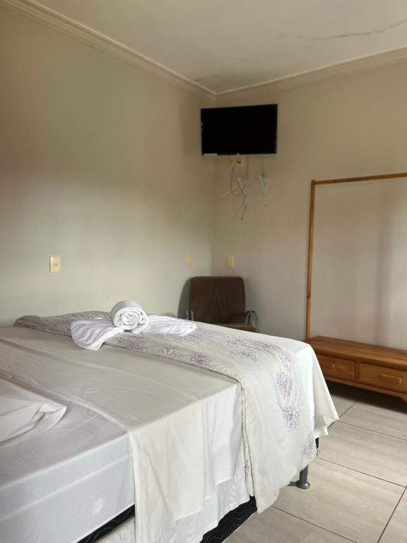 a bedroom with a bed with a white blanket at Hospedagem Riazo in Pirenópolis