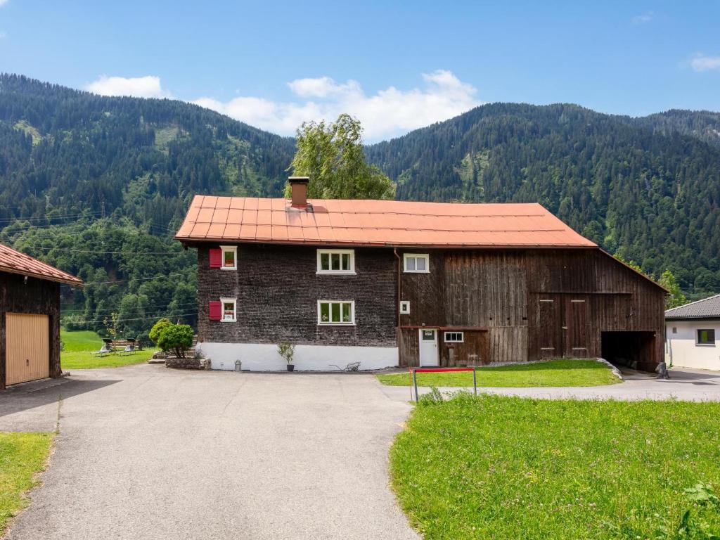 a barn with a red roof with a mountain in the background at Bühelhus in Dalaas