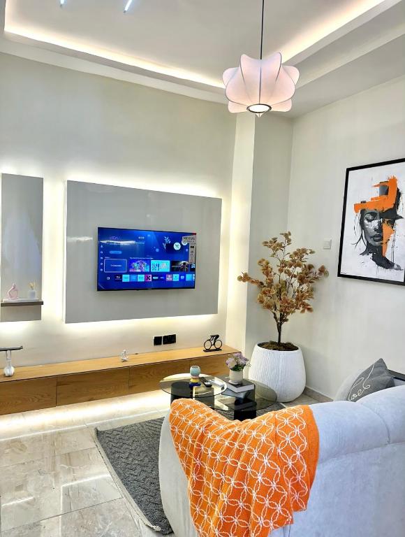 a living room with a couch and a tv on a wall at Djp in Lekki
