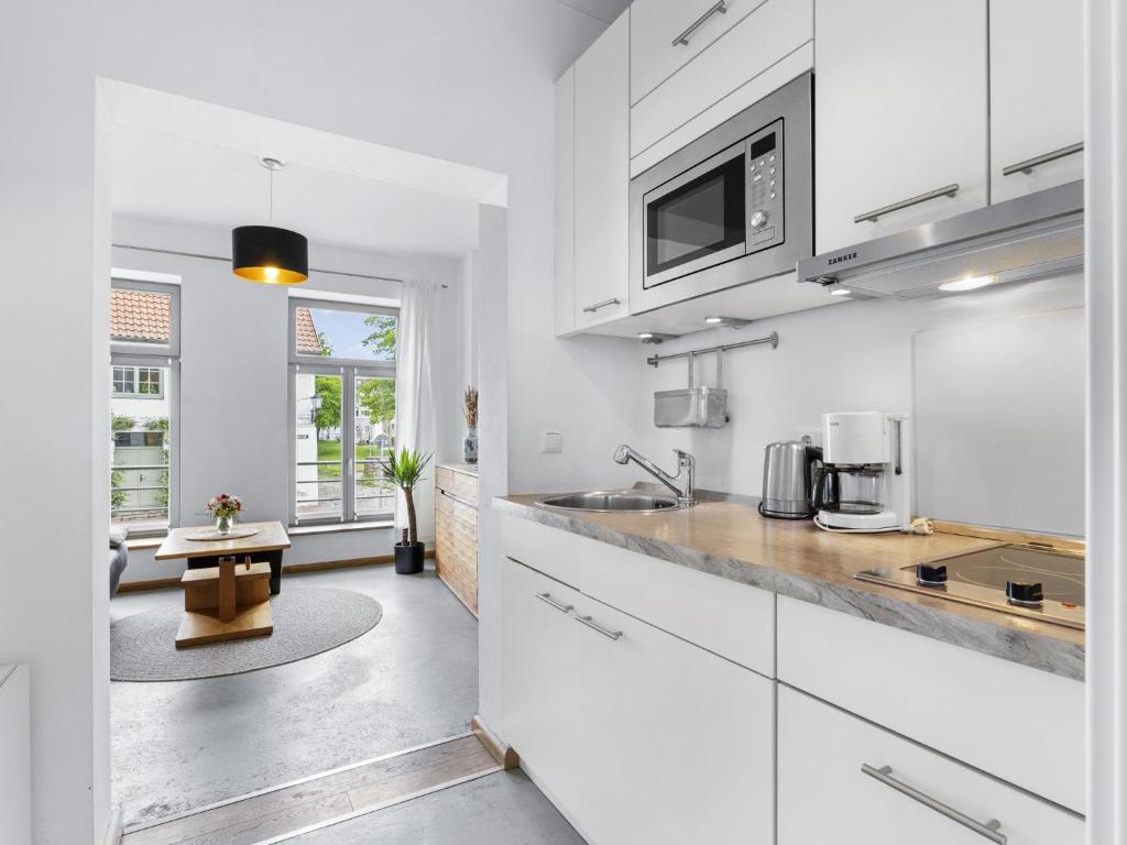 a kitchen with white cabinets and a table at Lee in Wismar