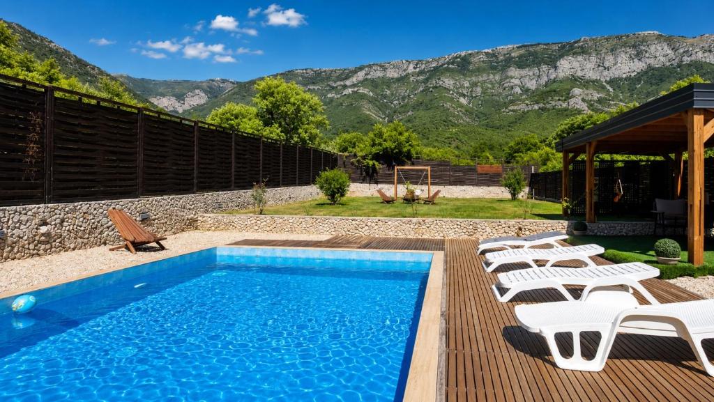 a swimming pool with chairs and a table and mountains at Vila Dar Selam halal-friendly in Mostar