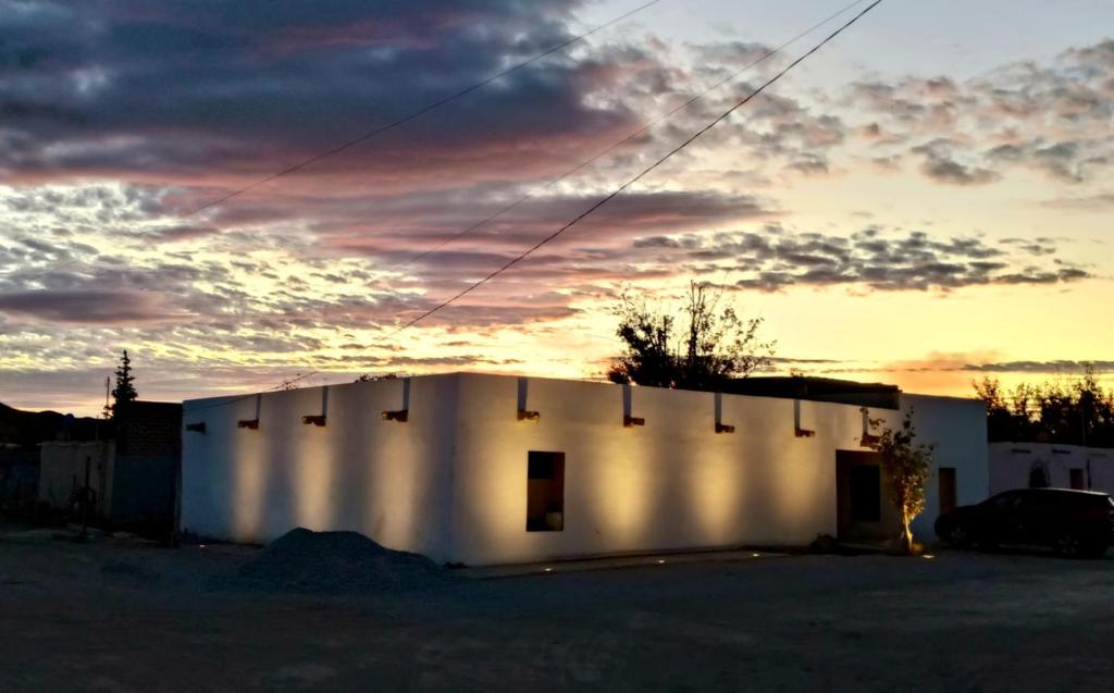 a white building with a sunset in the background at Tu hostalito en Parras in Santa Isabel