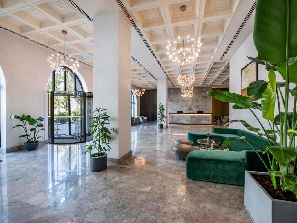 a lobby with a green couch and potted plants at Tbilisi Philharmonic Hotel by Mercure in Tbilisi City