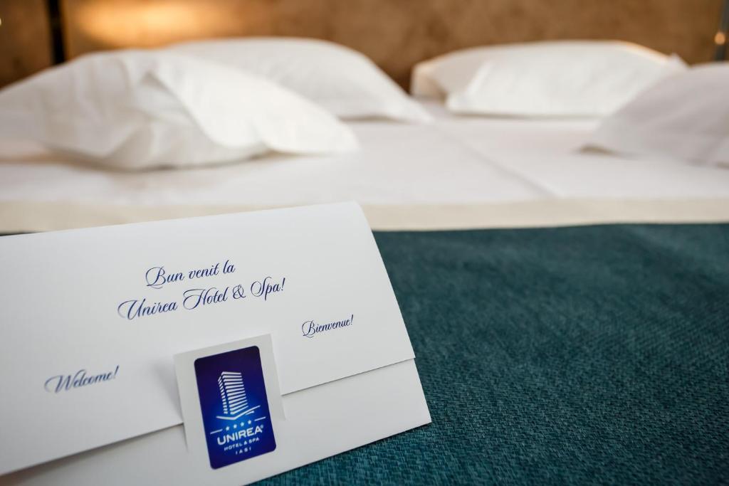 a hotel room with two beds and a card on a table at Unirea Hotel & Spa in Iaşi